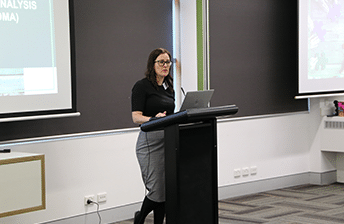 Dr Megan Finch-Edmondson standing at a podium presenting results of the world’s largest data analysis of cord blood for CP