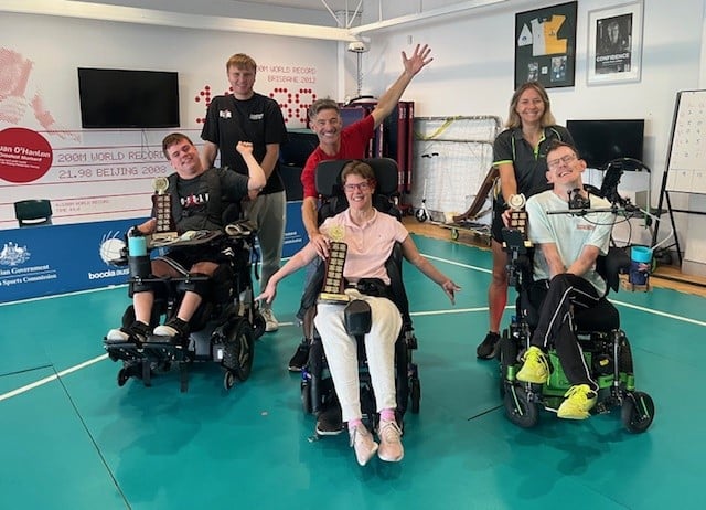 Wheelchair Boccia players lined up for a photo with their trophies