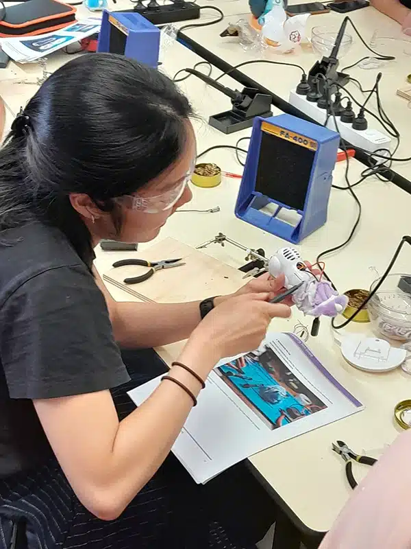 A female participant working on a toy with pliers at the switch adapt workshop