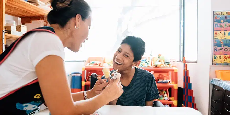 Teacher playing with boy with Cerebral Palsy in Classroom