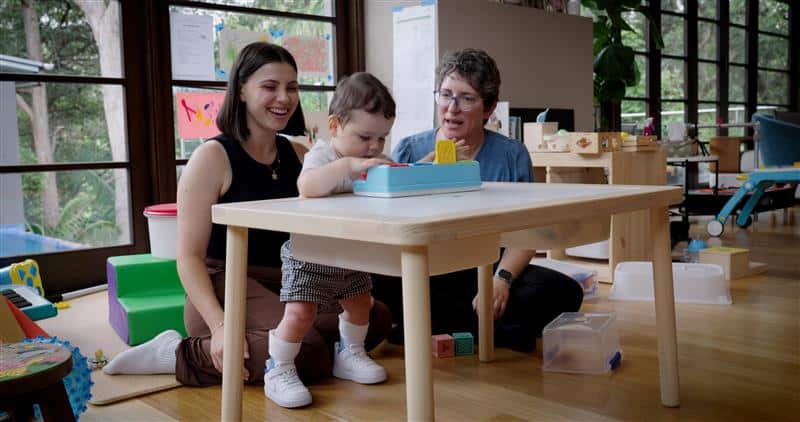 Therapist and mother supporting infant with cerebral palsy during early intervention session