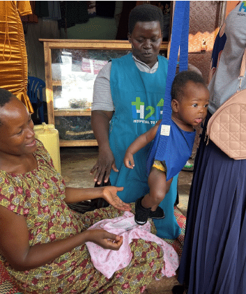 A baby being weighed during a Hospital to Home visit in Uganda in 2025
