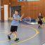 Two males playing tennis in a gym