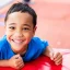 A young boy, Noah, leaning on a red crash mat, smiling to camera.