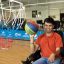Young adult male in a wheelchair playing basketball in a gym