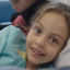 Zara smiling into the camera lying in bed during cord blood treatment.