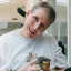 Sam holding a guinea pig in his hands, smiling to camera