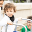 A toddler standing at the top of a slippery-dip with a male and female therapist looking on.