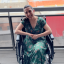 Woman with dark hair in wheelchair wearing green dress smiling