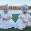 Twin baby girls Heidi and Sadie sitting on the grass in front of a lake.