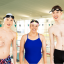 Three young adults standing together in their swimwear at a pool, ready to swim