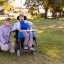 A middle age client in a wheelchair in the park with his support worker