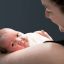 A newborn baby with a feeding tube being held by her mother