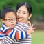 An Asian mother smiling to camera while hugging her young son with down syndrome