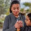 A tender moment as a boy with cerebral palsy holds his mother's hand during an outdoor interaction.