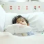 A young boy lying in a hospital bed with bandages on his arm