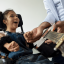 A teenage girl in a wheen chair learning to play guitar.